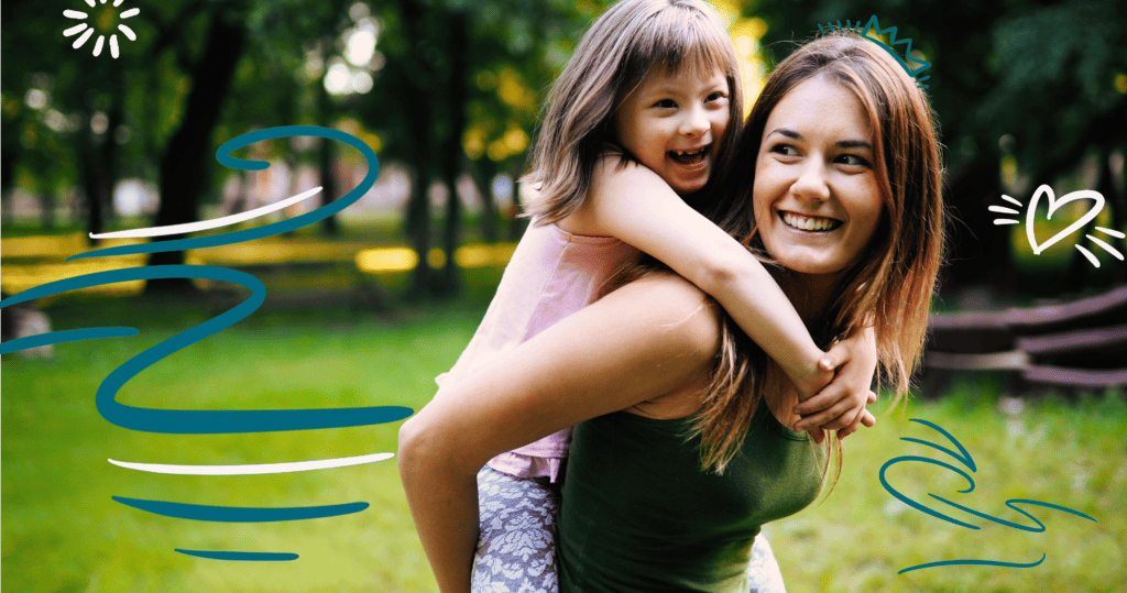 Young, smiling woman giving a special needs girl a piggyback ride in a park