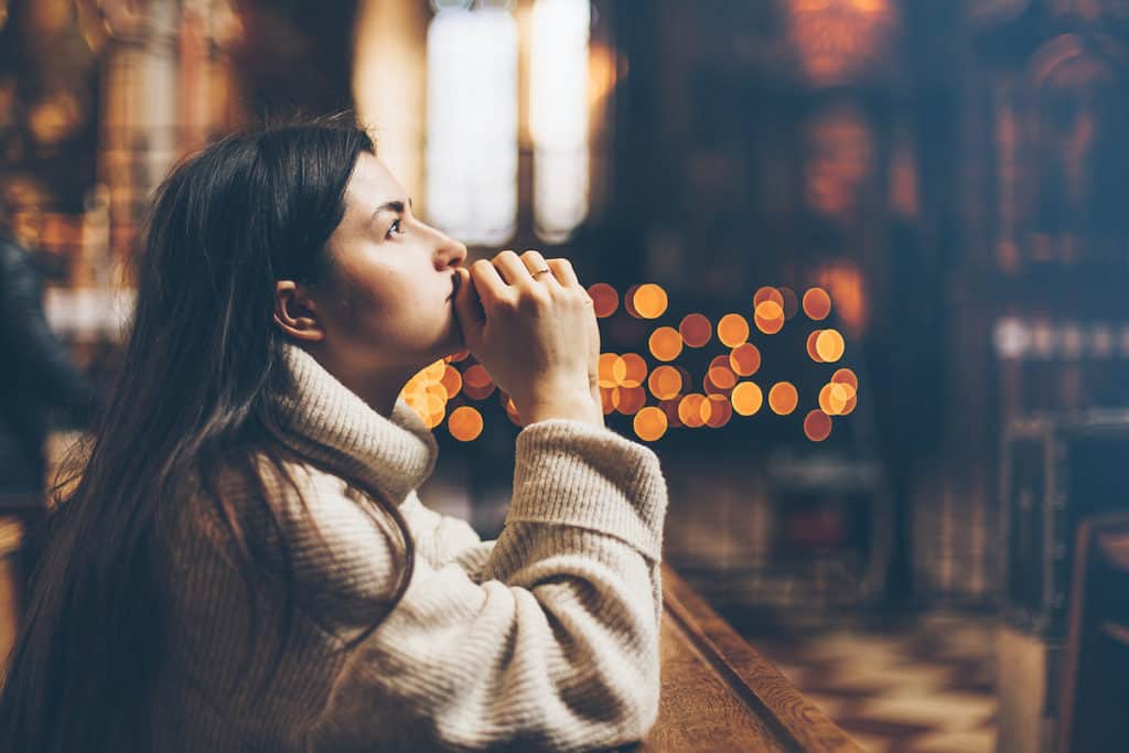 a woman prays alone in a church