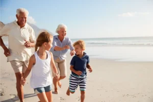 Grandparents and two grandchildren running on the beach
