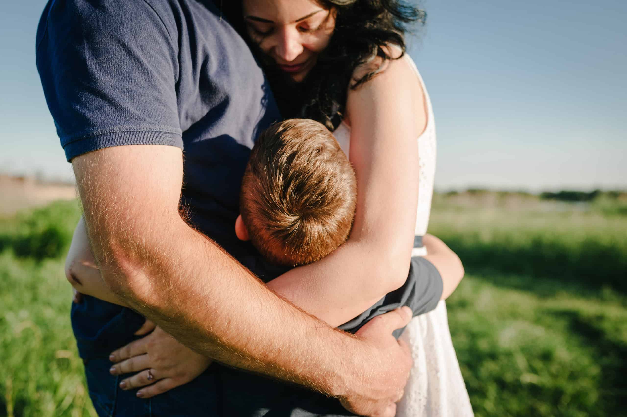 a man and his wife hug their son