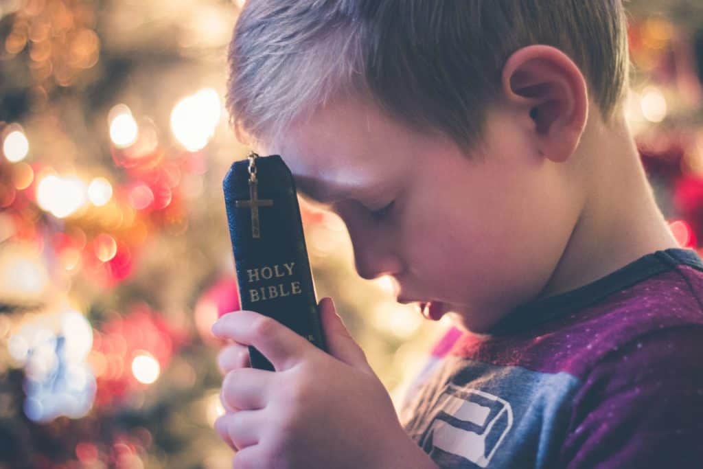 25 Bible Verses for Kids to Memorize as boy holds Bible