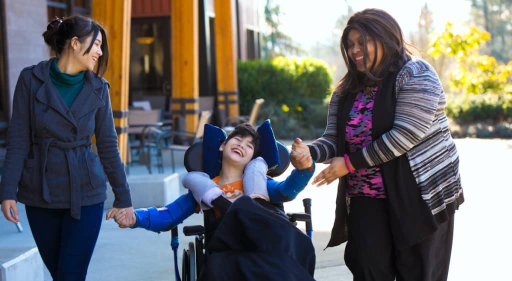 Two women help a child with special needs with how to engage with God.