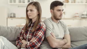 a young woman and man sit back to back after an argument