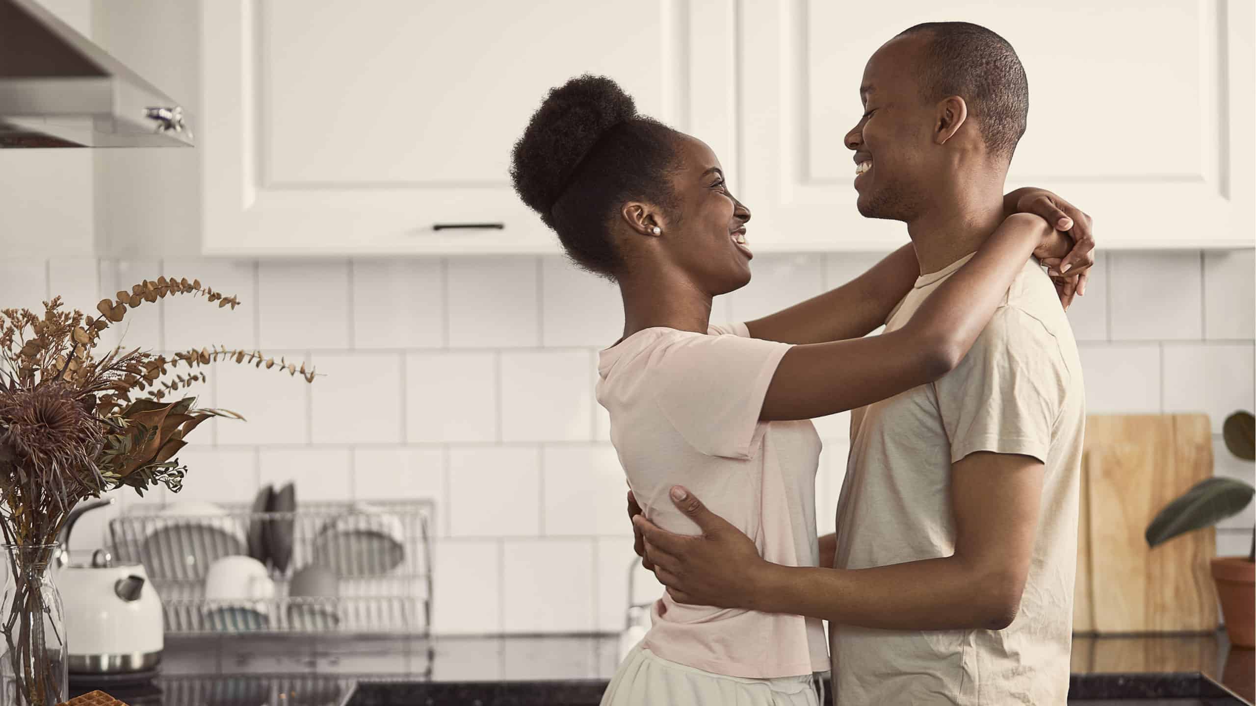 a man and woman dance together in a kitchen.