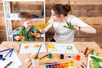Mom and young son having fun making handprints with paint