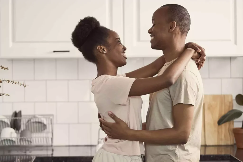 A smiling couple embraces warmly in a kitchen, highlighting the importance of spending quality time together.