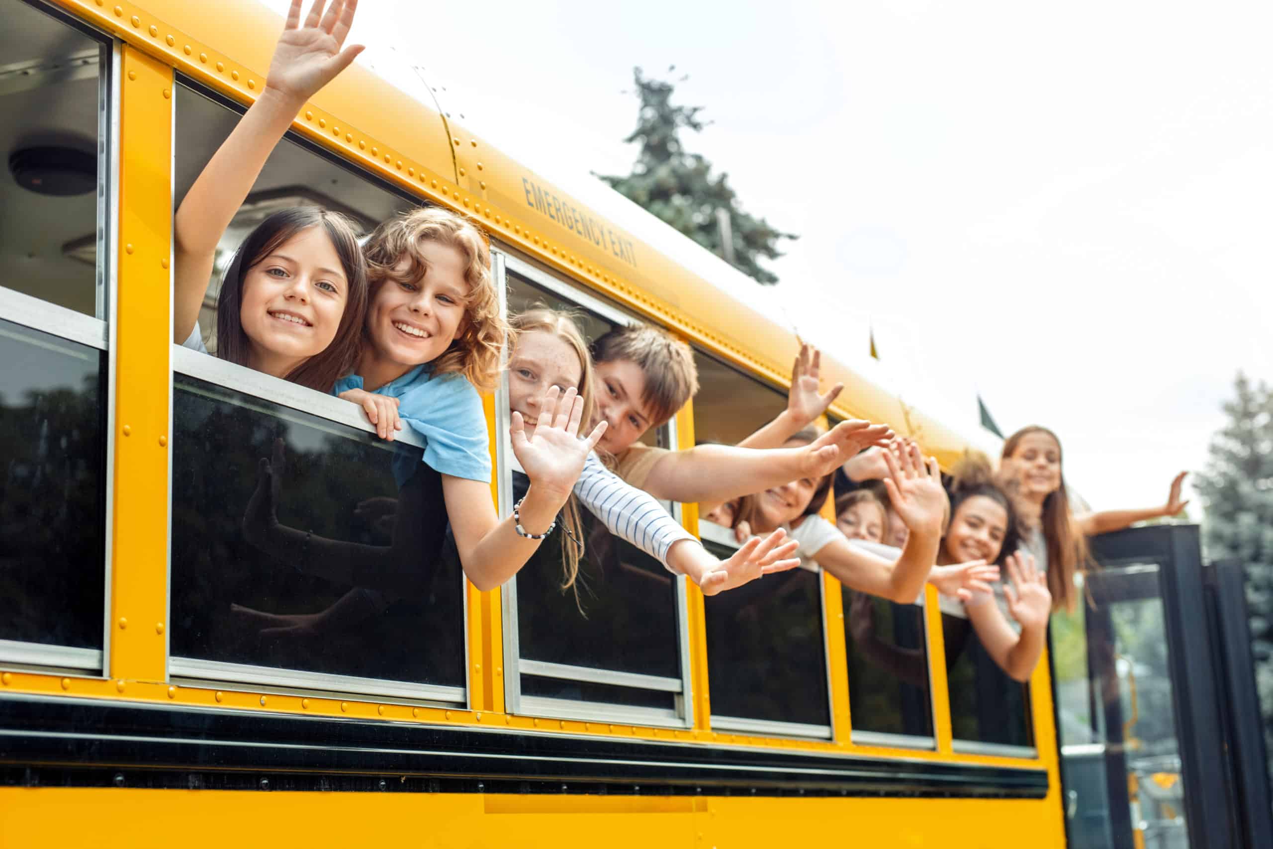 Children waving from bus windows