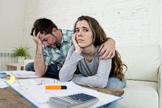 Couple working on financial paperwork and looking distressed