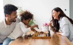 new traditions - Happy family playing chess together at home