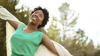 Joyful African-American woman with outstretched arms covered by a shawl, looking like she's dancing