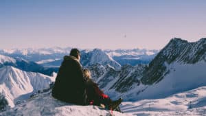 Couple on snowy mountain peak looking out