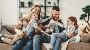 Husband and wife laughing with children on couch