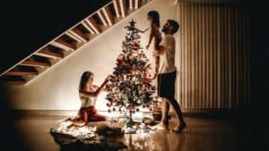 Husband and wife setting new traditions in marriage decorating the Christmas tree with daughter