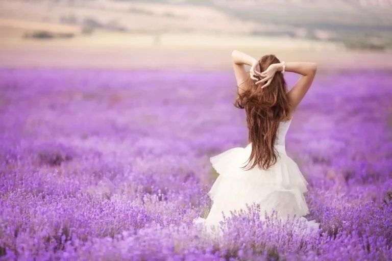 A newlywed bride walks through a field of purple wild flowers. Here are 12 pieces of advice the author would share with her newlywed self.