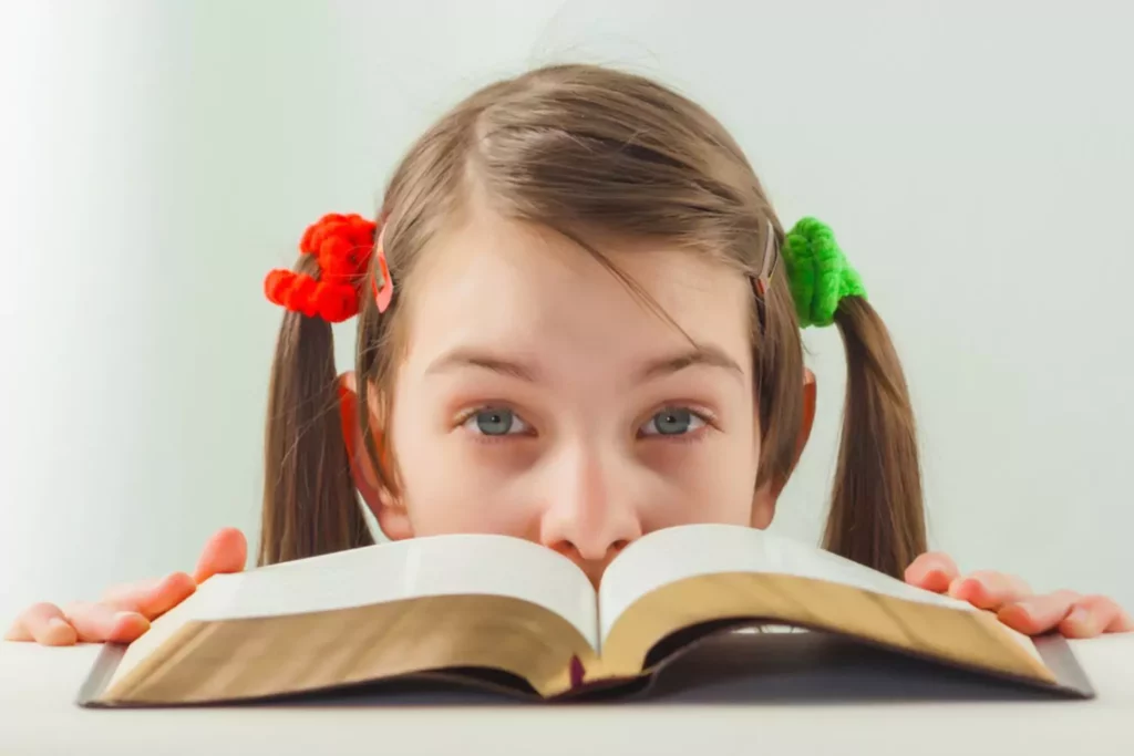 Young girl peeking over her bible