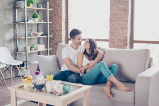 Smiling couple in a romantic brace while relaxing on their couch at home