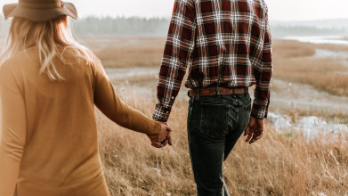 Man and women walking in field holding hands
