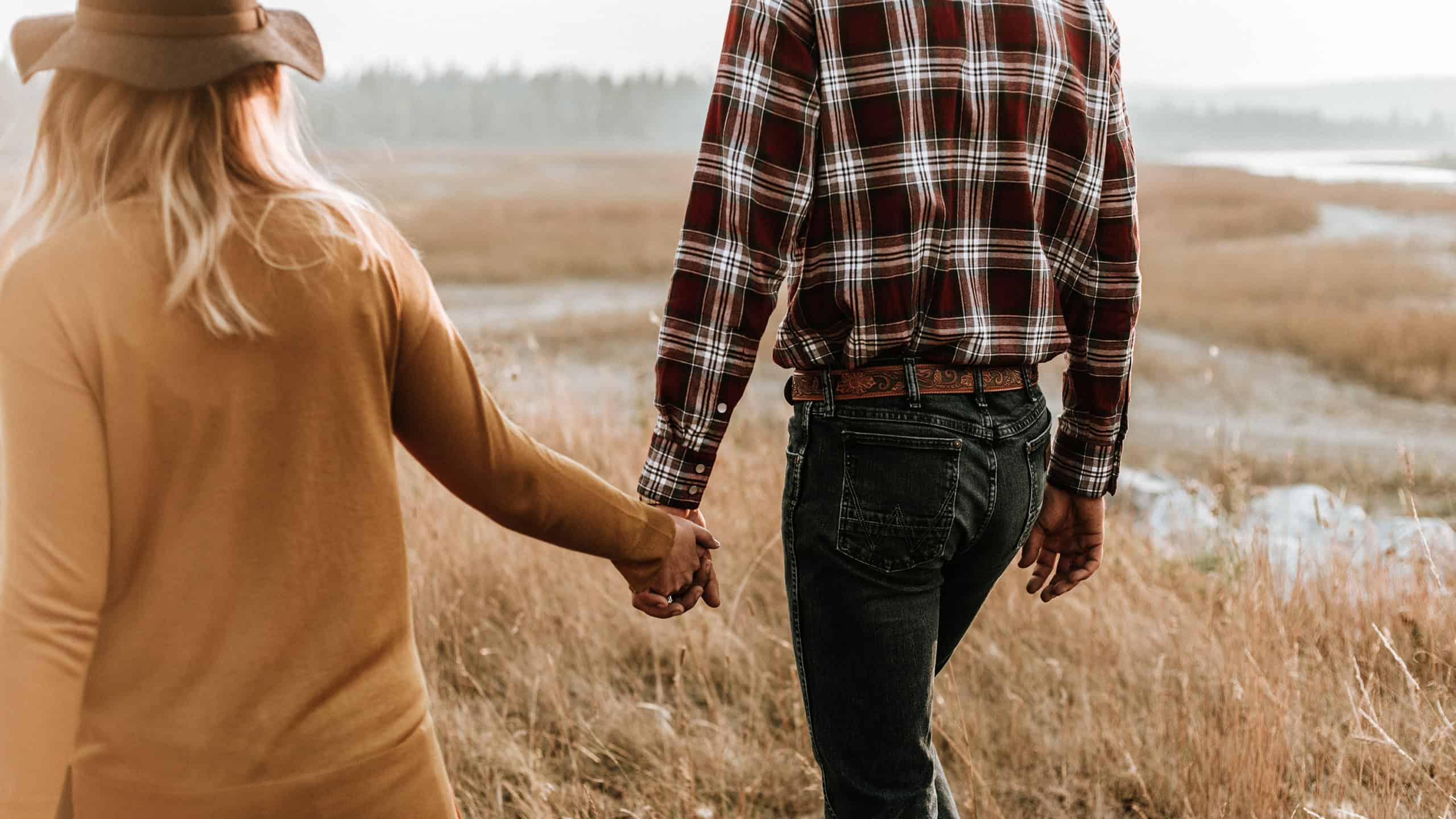 Man and women walking in field holding hands