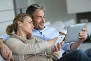 A man and woman watch content on an iPad