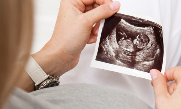 Close-up of an ultrasound photo being held by mom's hands while she sits in hospital bed