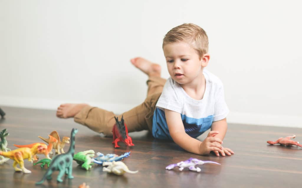 Little boy playing with dinosaur and animal action toys at home