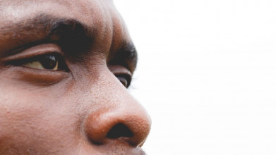 Close up of a black man's face. He has a serious look, with a slightly furrowed brow.