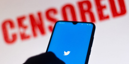 Close up of a smartphone with the Twitter logo displayed, and the word 'Censored' in big red letters in the background