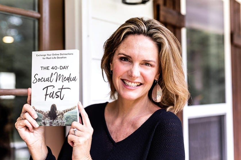 Author Wendy Speake smiling as she holds up her book "The 40-Day Social Media Fast"
