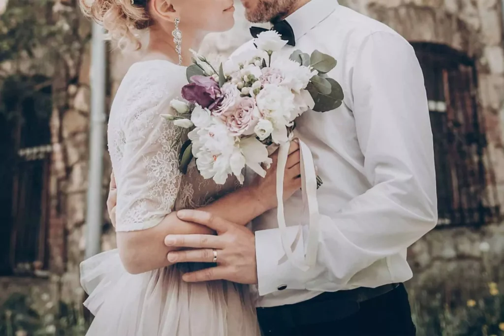 stylish wedding couple with bouquet. modern bride and groom holding fashionable bouquet at old castle.