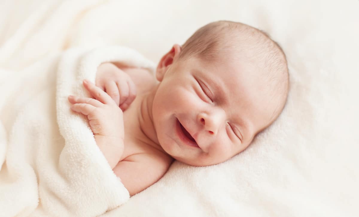 A newborn baby girl smiles as she is blessed with a pro-life prayer.