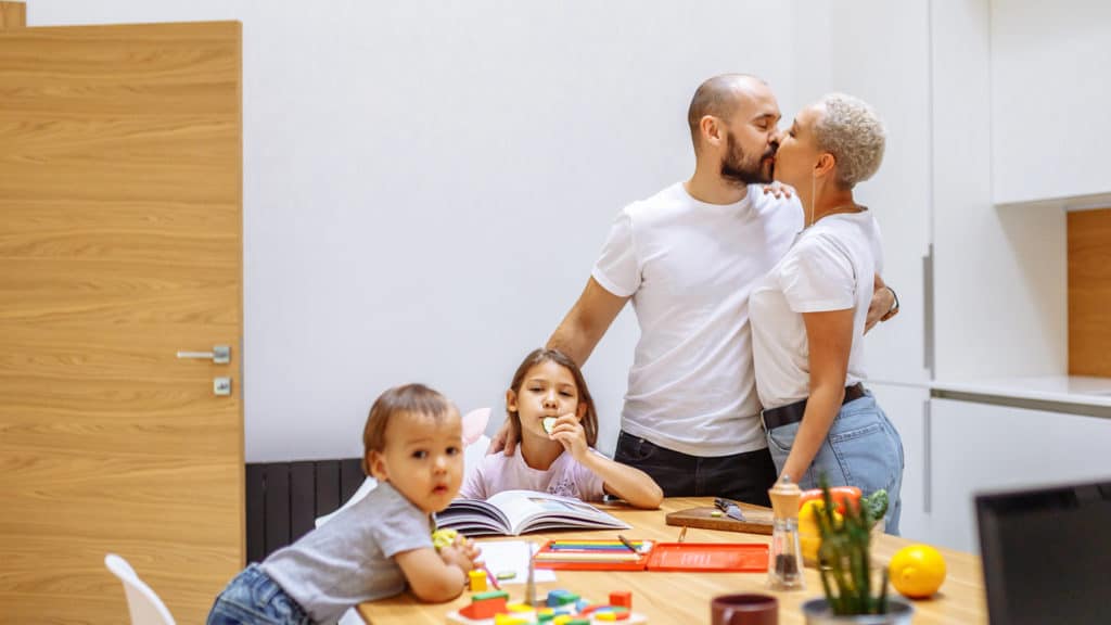 Husband and wife kissing in front of kids prioritizing marriage in a their family