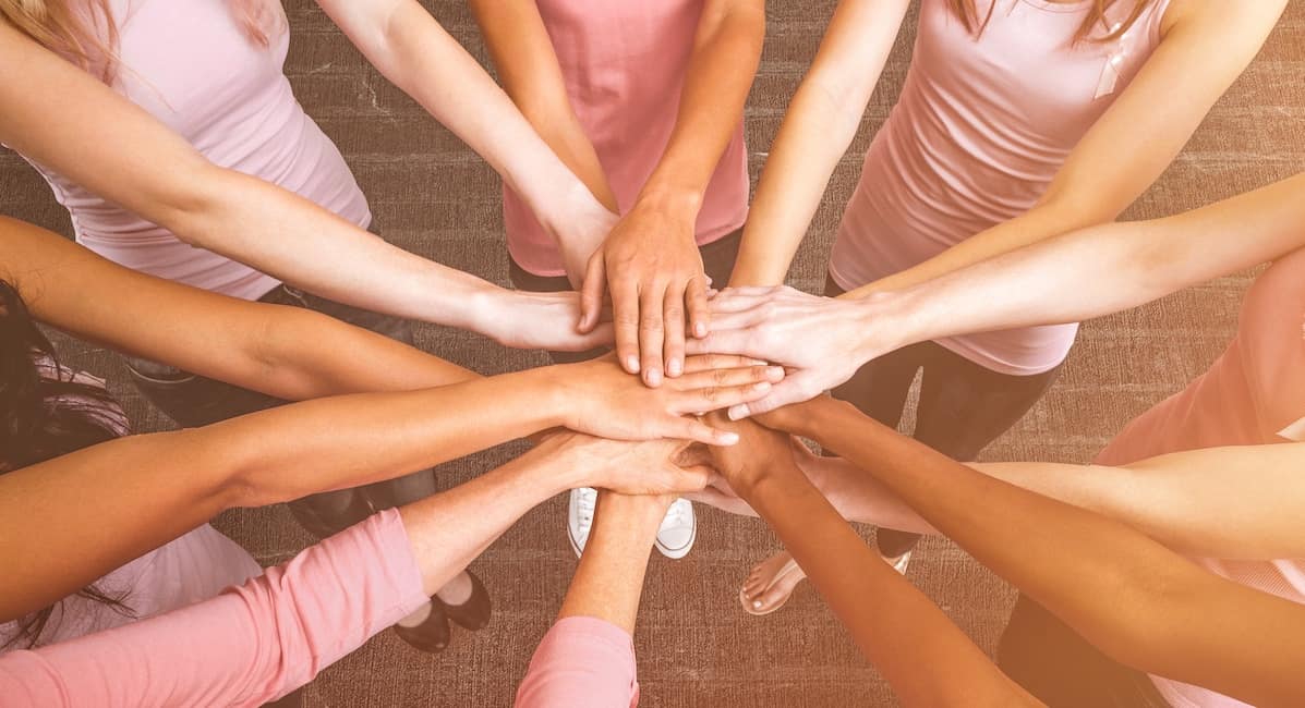 women in pink join hands as empowered women empower women