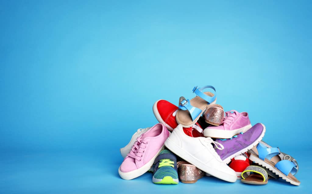 Heap of different shoes on color background