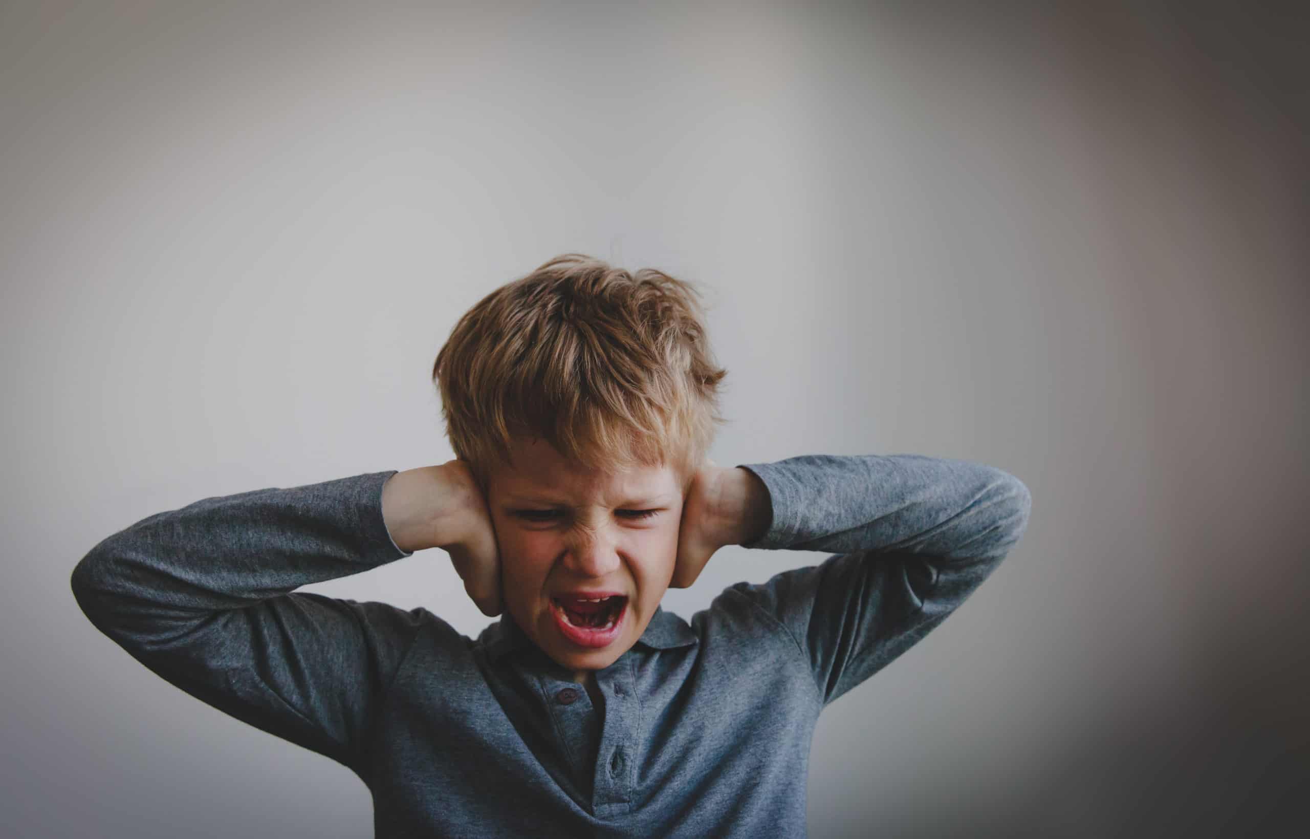 young boy from hard place covering ears in anger