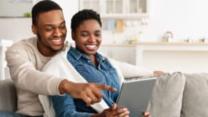 African American couple looking at tablet together on couch