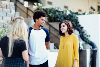Group of three young people standing outside having a conversation