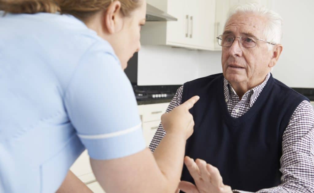 Angry woman scolding an elderly man who appears a little fearful and defensive. This is elder abuse.