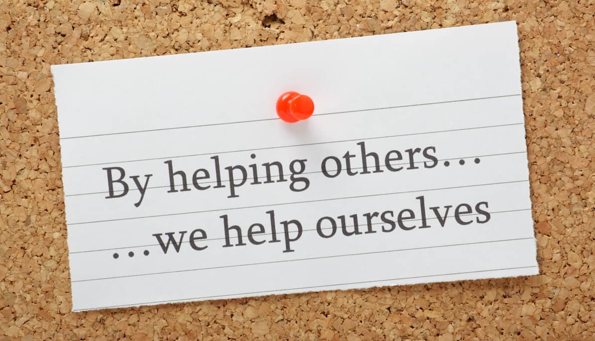 A card with an example of kindness quotes saying, "By helping others... we help ourselves."
