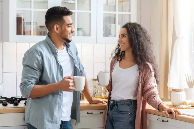 A couple smiling and enjoying coffee together in a kitchen, representing healthy gender roles in marriage through mutual respect and open communication.
