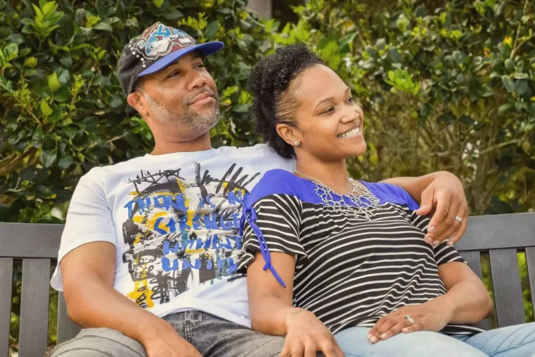 A happy couple relaxes on a park bench, leaning into each other and smiling, symbolizing the joy and connection that comes when you refresh your marriage.