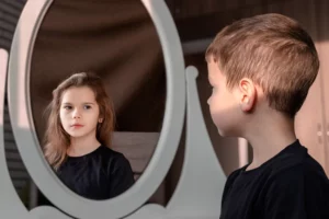 Gender identity issues. Boy looking into a mirror and seeing himself as a girl.