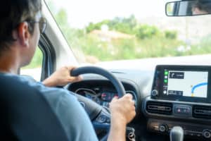 Photo of a man at a steering wheel, following a GPS map.