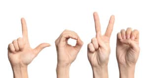 four hands use American sign language to sign word LOVE to Deaf community.