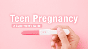 Pink background, woman's hand holds positive pink lines pregnancy test for Teen Pregnancy resources teen mom