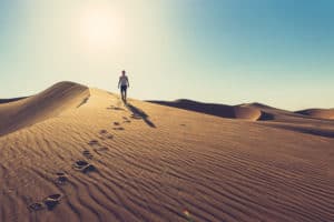 Photo of a man wandering through a desert.