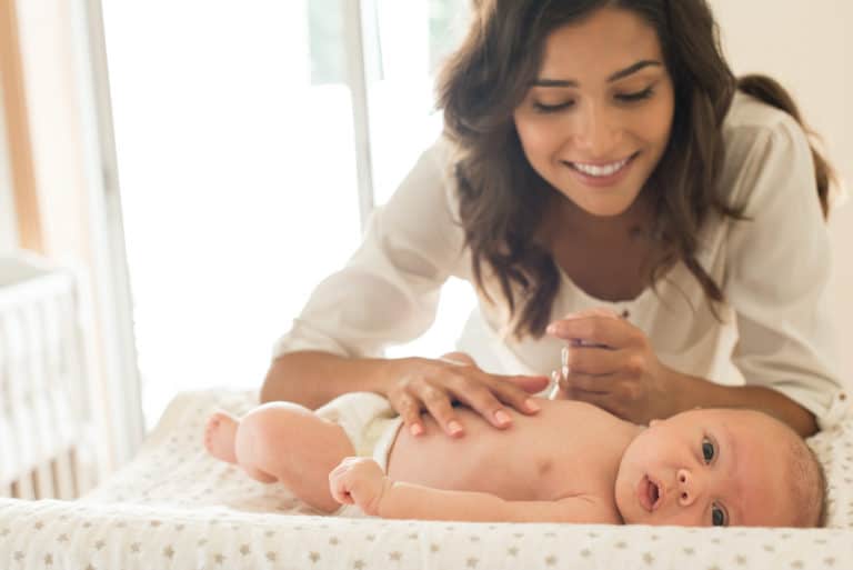 A birth mother in open vs closed adoption cares for her newborn on a changing table.