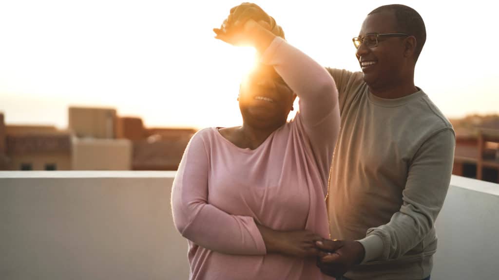 Middle aged African American couple dancing on a rooftop at sunset