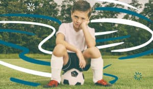 Boy sitting on soccer ball, feeling stuck