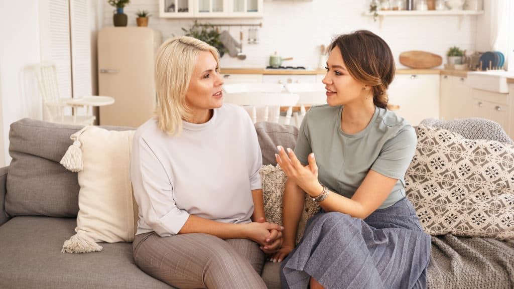 Young woman and middle age woman sitting on a couch having a discussion