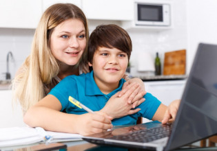 Mom hugging her tween son from behind as they both look at a laptop screen